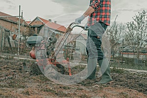 Farmer performing garden tillage with an old motor cultivator