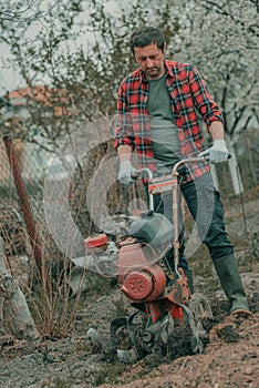 Farmer performing garden tillage with an old motor cultivator