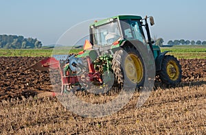 Farmer plowing the harvested cornfield