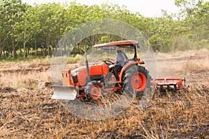 Farmer plowing stubble field with orange tractor