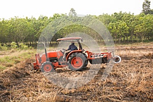 Farmer plowing stubble field with orange tractor