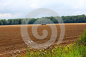 Farmer plowing stubble field with red tractor