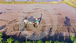 a farmer plows a field with a hand tractor farming machine in a terraced rice field