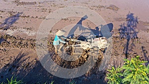 a farmer plows a field with a hand tractor farming machine in a terraced rice field