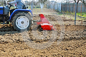 Farmer plows the field. Small tractor with a plow in the field. Cultivation