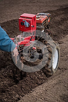 Farmer plows the land with a cultivator, preparing it for planting vegetables