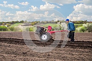 Farmer plows the land with a cultivator, preparing it for planting vegetables