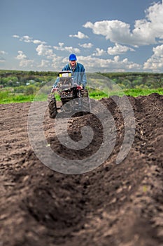 Farmer plows the land with a cultivator, preparing it for planting vegetables