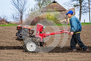 Farmer plows the land with a cultivator, preparing it for planting vegetables