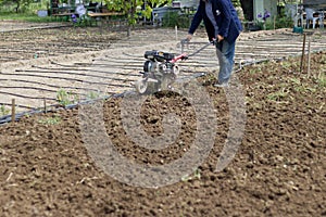 A farmer plows the land with a hand-held motor plow. Agricultural machinery: cultivator for tillage in the garden, motorized hand