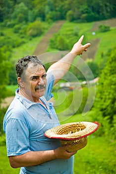 Farmer pointing to his plowing land on hill