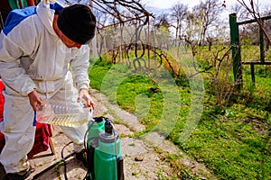 Farmer is pouring substance for sprinkling fruit trees in plastic knapsack sprayer