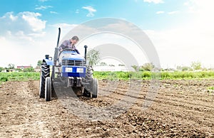 Farmer is processing soil on a tractor. Soil milling, crumbling mixing. Loosening surface, cultivating land for further planting.