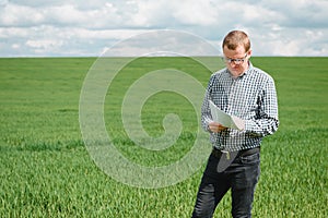 Farmer in red checked shirt using tablet on wheat field. Applying modern technology and applications in agriculture. Concept of