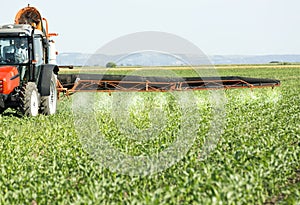 Farmer in red tractor spraying soybean field photo