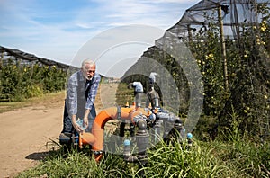 Farmer repairing valve irrigation system in orchard