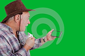 A farmer with a runny nose talks on a smartphone with a chroma key screen.