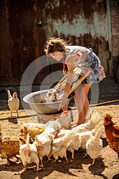 Farmer`s daughter is washing his father`s shirt in courtyard, surrounded by chickens. A cute girl is happy, helping family