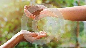 farmer's hand poured fertile soil into the hands that supported the bottom,The concept of abundance in the soil, preserving