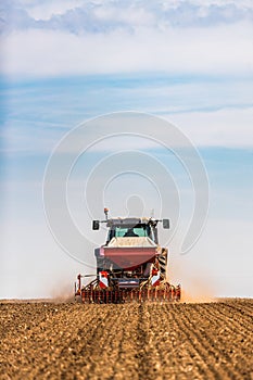 Farmer seeding, sowing crops at field.