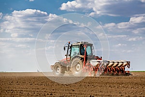 Farmer seeding, sowing crops at field.