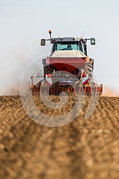 Farmer seeding, sowing crops at field.