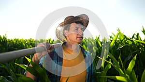 farmer with shovel walk in corn field. agriculture a corn business concept. light farmer man with shovel and walk along