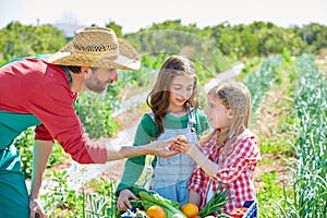 Farmer showing vegetables harvest to kid girls