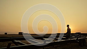 Farmer silhouette stand wheat field at golden sunset. Agro machinery concept