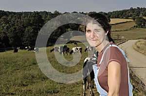 Farmer sitting on a fence and behind her herd of cows photo