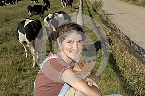Farmer sitting on a fence and behind her herd of cows photo