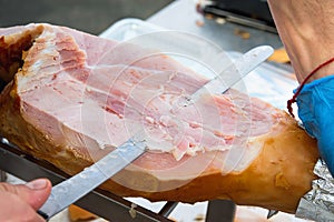 Farmer Slicing with Long Knife Smoked Baked Pork Ham from Leg at Market. Close up of Meat Texture. Vibrant Colors. Organic Produce