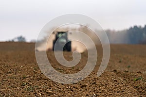 A farmer sowing with a John Deere tractor in the background photo