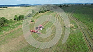 The farmer speeds up the drying of the hay by moving the harvested hay with the help of a tractor tedder. Top wiev.