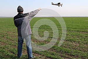 A farmer standing on his wheat field points at a small airplane.