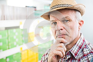 Farmer at supermarket with hand on chin