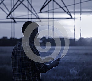 Farmer with tablet in front of irrigation system