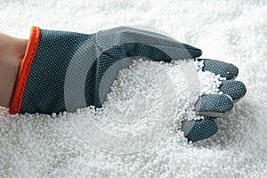 Farmer taking pellets of ammonium nitrate from pile, closeup. Mineral fertilizer