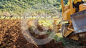 Farmer tills the soil with the crawler tractor. Agriculture