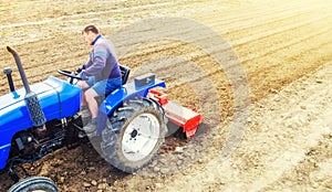 A farmer on a tractor cultivates a farm field. Field land preparation for new crop planting. Grinding and loosening soil, removing