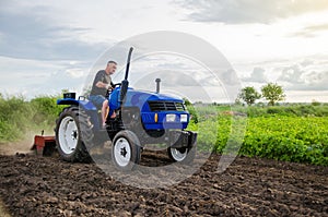 Farmer on tractor cultivates farm field. Milling soil, crushing and loosening ground before cutting rows. Farming, agriculture