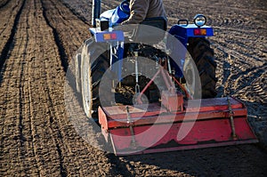 A farmer on a tractor cultivates a farm field. Softening the soil and preparing for cutting rows for the next sowing season in the
