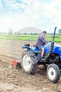 A farmer on a tractor cultivates a farm field. Soil milling, crumbling and mixing. Loosening the surface, cultivating the land for