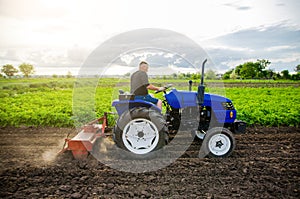 A farmer on a tractor cultivates a field. Farm work. Milling soil, Softening the soil before planting new crops. Farming. Plowing photo
