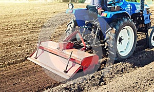 Farmer on a tractor cultivates land after harvesting. Development of agricultural technologies. Grinding loosening plowing
