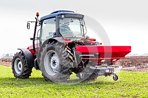 Farmer in tractor fertilizing wheat field at spring with npk