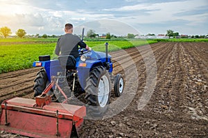 A farmer on a tractor looks at the farmer`s field. Work on the plantation, preparing the soil for subsequent planting