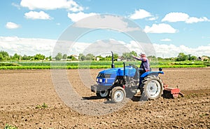 A farmer on a tractor with a mill unit crushes and processes the soil for further sowing with agricultural crops. Loosening
