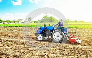 Farmer on a tractor with milling machine loosens, grinds and mixes soil. Field preparation for new crop planting. Work on