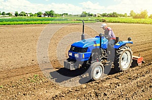 Farmer on a tractor with a milling machine processes loosens soil in the farm field. Grind and mix soil on plantation. Preparation